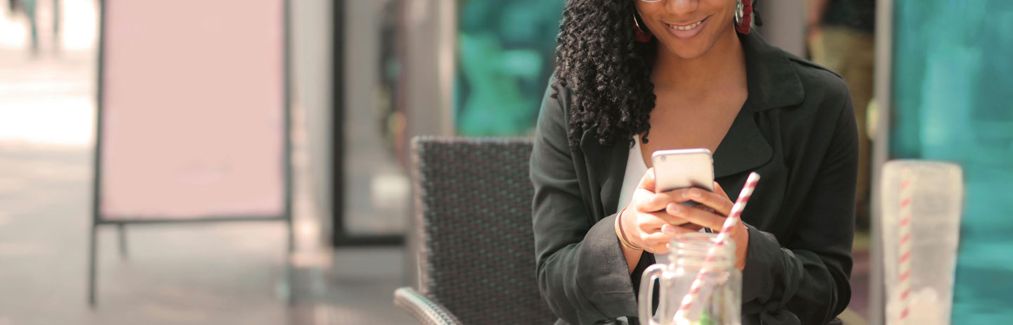 Cropped photo of woman sitting outside at café and using a smartphone