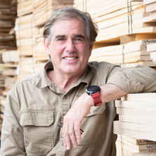 Close up photo of man leaning his arm against a stack of lumber