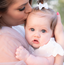 close up of mother holding baby daughter while kissing top of baby's head