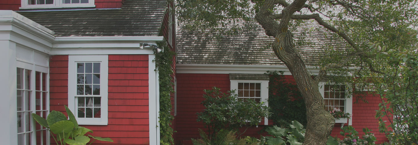 Cropped photo of red house with white trim with garden