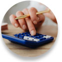 Close up photo of hand holding gold pen using a blue calculator