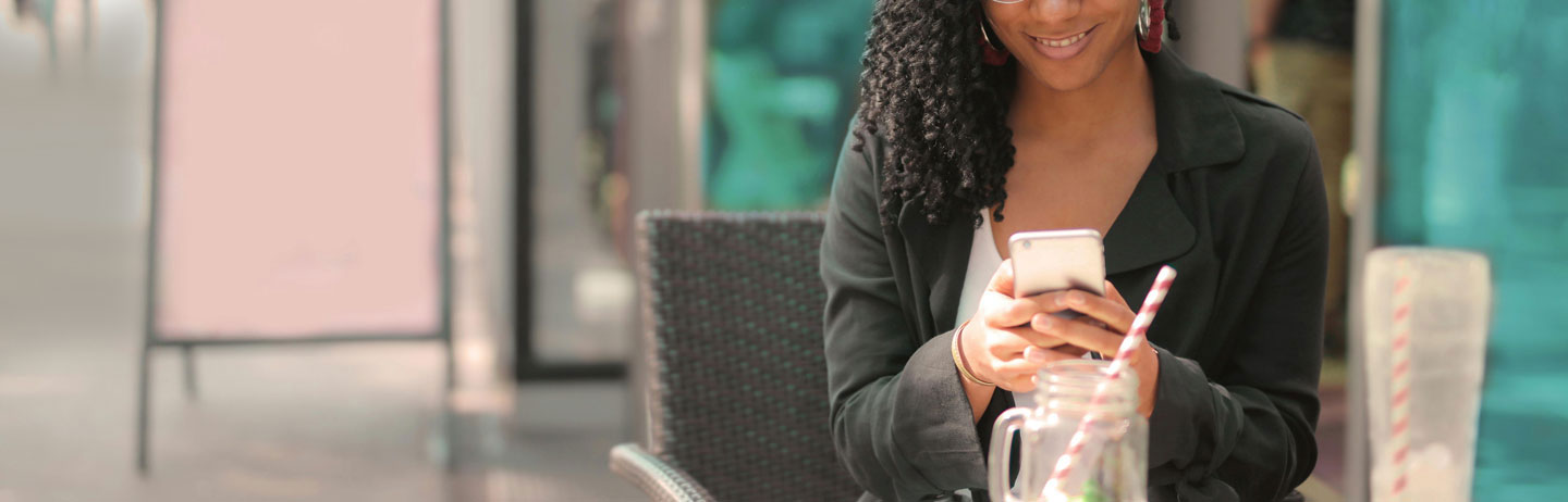 Cropped photo of woman sitting outside at café and using a smartphone