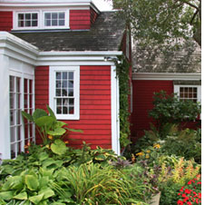 Red house with flowers and hosta plants in yard