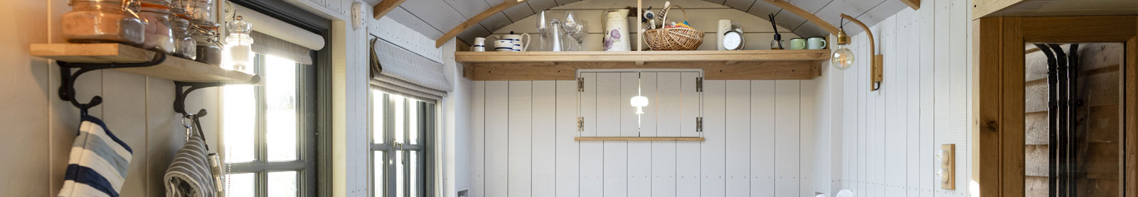 Interior photo of a tiny home with white paneled wooden walls and ceiling