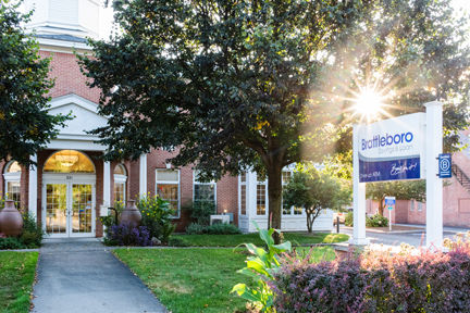 summertime photo of BS&L's main office in brattleboro with bank sign and sunshine streaming through trees and bright green grass