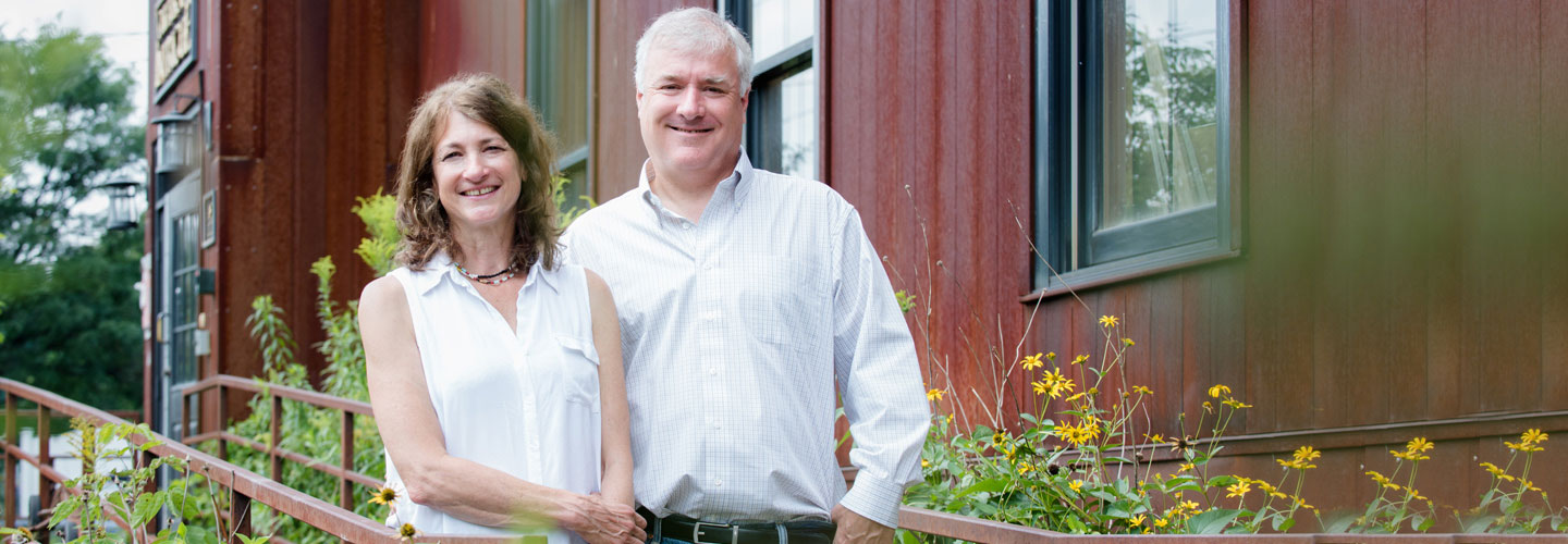 Happy couple standing in front of dark red building
