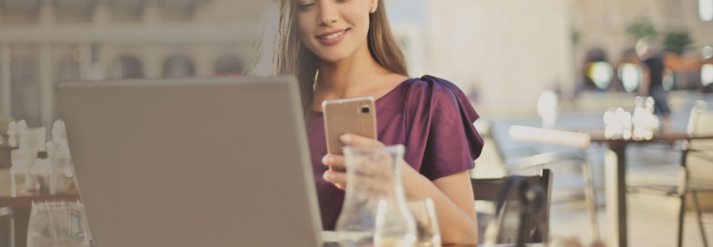Woman looking at smartphone and laptop