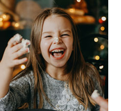 laughing girl with frosting on her nose and holiday lights in background