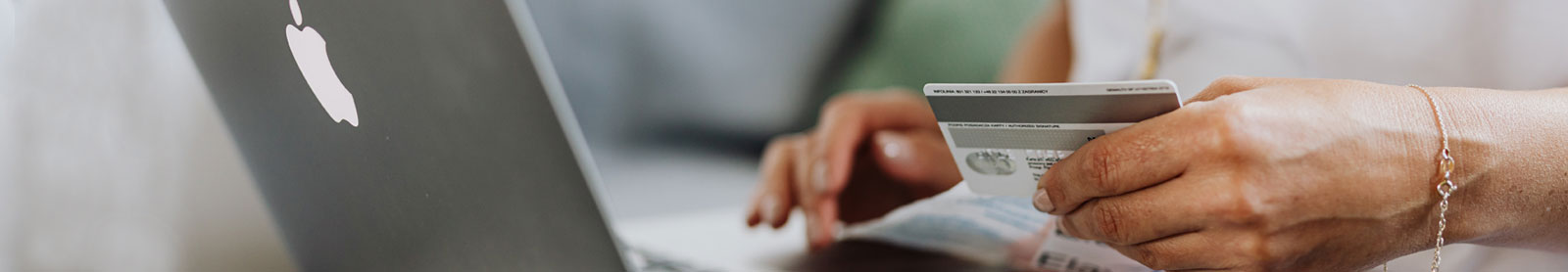 Cropped photo of laptop with woman's hands holding a credit card
