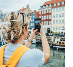 Woman holding her phone and taking a photo on vacation in a beautiful European waterfront destination