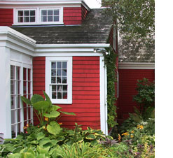 cropped photo of red house with cedar shake roof and white trim with hosta garden