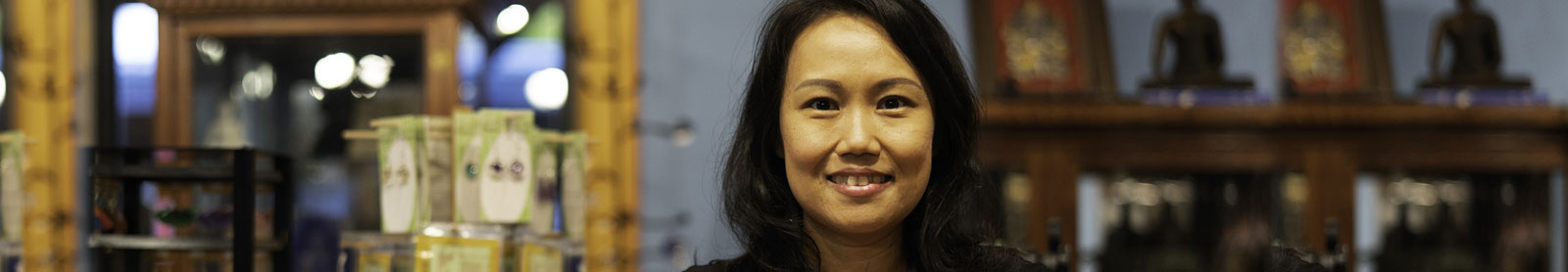 Close up of woman business owner standing in her store with earing display rack and other display shelf behind her